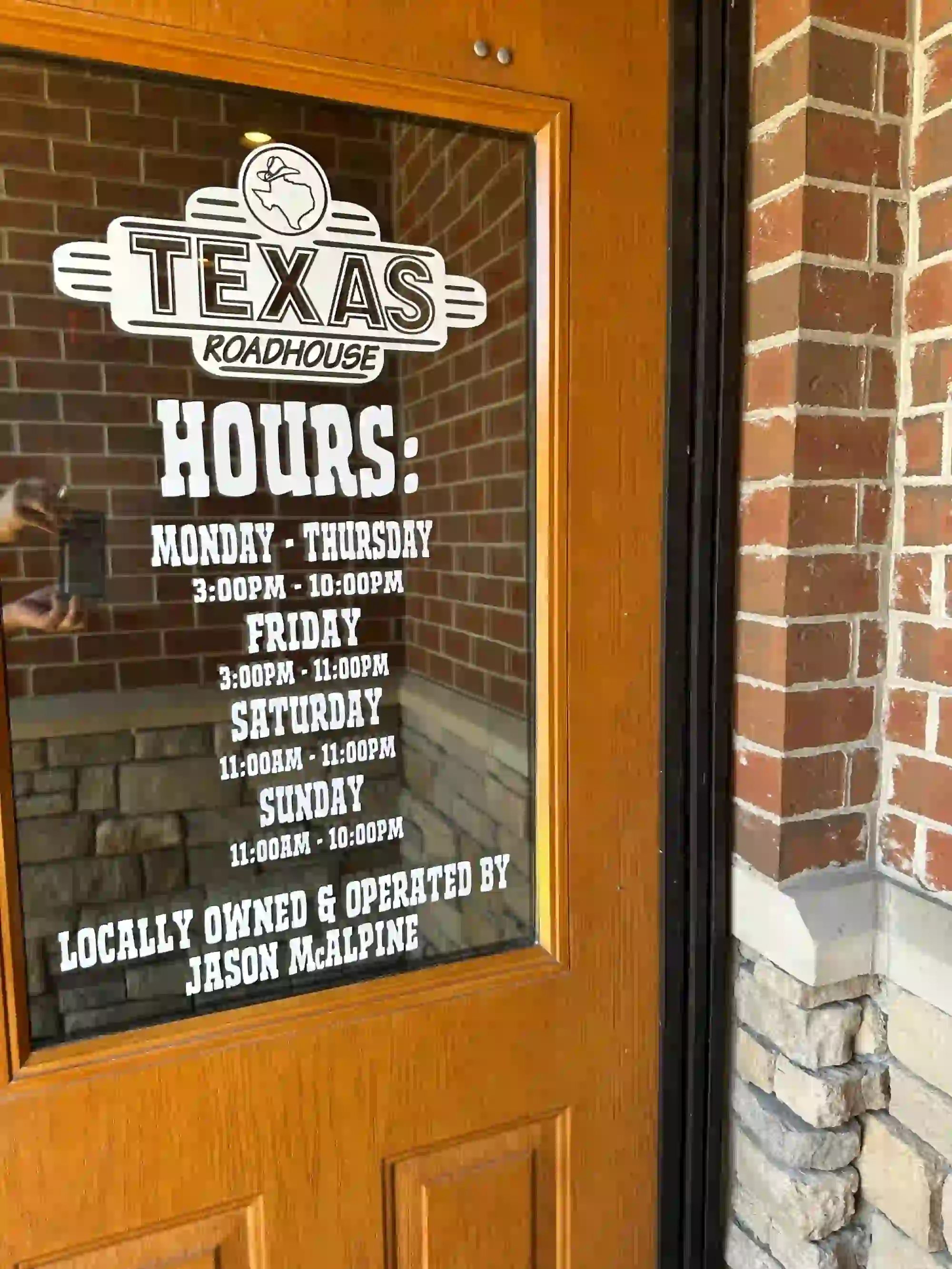 Texas Roadhouse business hours posted on the entrance door in Arnold, MO